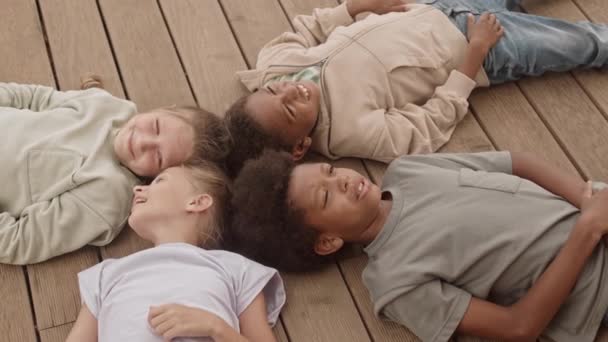 Slowmo Four Multiethnic Kids Lying Together Back Wooden Planks Talking — Stock Video