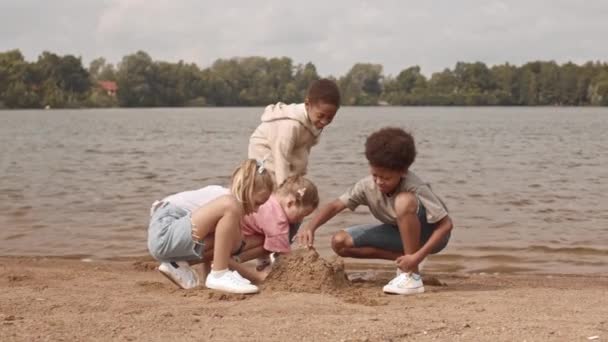 Слово Четырех Веселых Многоэтнических Детей Которые Строят Песчаный Замок Берегу — стоковое видео