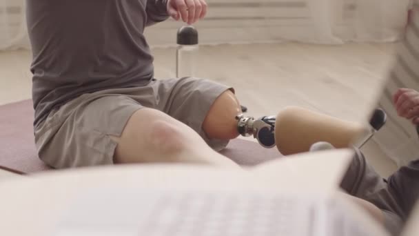 Yoğunlaşmış Protez Bacaklı Antrenman Minderinin Üzerinde Otururken Sırtını Esneten Beyaz — Stok video