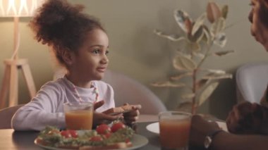 6 yaşında güzel bir Afro-Amerikan kızın ev yapımı sandviçlerini yerken ve mutfak masasında oturan sevgili annesiyle konuşurken belini kaldır.