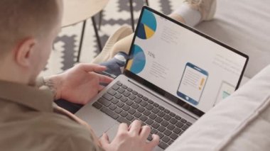 Ev ortamında rahat bir atmosferde çalışırken dizüstü bilgisayardaki pazarlama istatistiklerine bakan protez bacaklı iş adamlarının yavaş çekimleri.