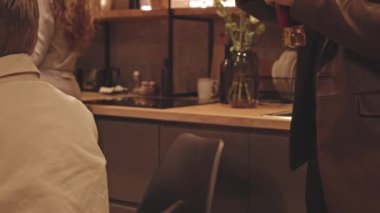 LGBTQ 'lu arkadaşlarla loş ışık altında mutfakta küçük bir akşam yemeği partisi yaparken süslü elbiseli yakışıklı eşcinsel adamın buzdolabından bir şişe bira aşırması.