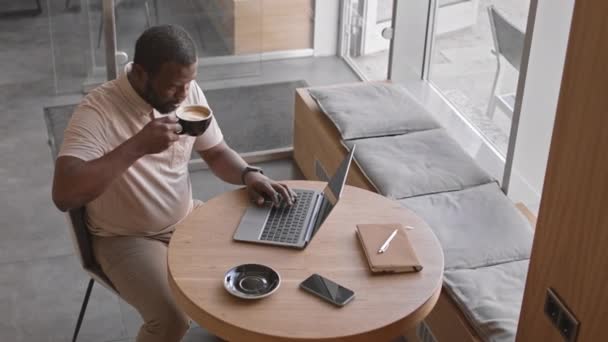 Top Widok Udanego Afroamerykańskiego Biznesmena Pijącego Cappuccino Pracującego Laptopie Siedząc — Wideo stockowe