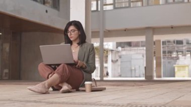 Sıcak yaz gününde modern iş merkezinin yakınında laptopla çalışan esmer bir iş kadınının yavaşlığı.