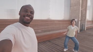 Genç siyahi adamın kendini ve kız arkadaşını kameranın önünde dans edip sosyal medya için video blogu çekerken elde taşınan POV yavaşlığı.