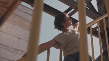 Yaz mevsiminde şantiyenin sarı merdivenlerinde yavaşça dans eden gevşek, kısa saçlı bir kadın.