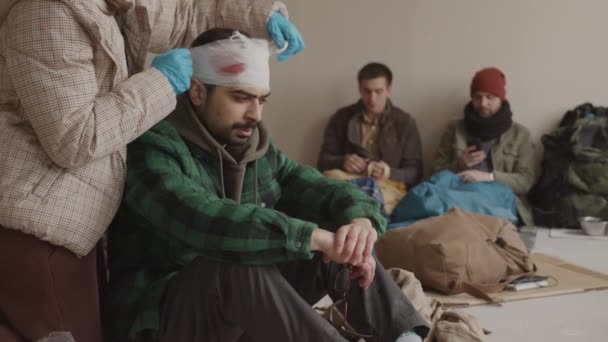 Slowmo Mulher Luvas Médicas Bandagem Cabeça Ferida Homem Refugiado Escondendo — Vídeo de Stock