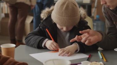 Diğer mültecilerle birlikte yerel yemek bankasında otururken şapkalı ve sıcak giyimli 7 yaşındaki beyaz çocuğu belden yukarı çek.