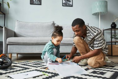 Genç Afro-Amerikan baba ve oğlunun boyalı boya kutusunu açarken evde yaratıcı aktivitelerin keyfini çıkardıkları, uzay kopyaları.