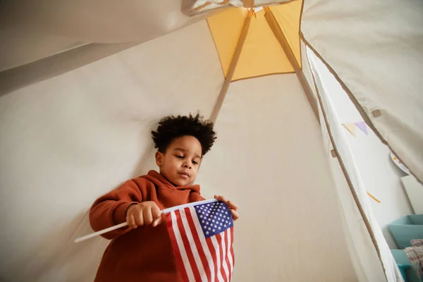 可爱的黑色幼儿在儿童帐篷里玩耍时举着美国国旗的低角度肖像 复制空间 — 图库照片