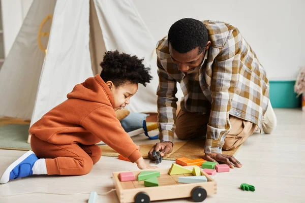 充满爱心的黑人父亲在舒适的孩子房间里和儿子在地板上玩耍的全长肖像 父亲身份和家庭观念 — 图库照片