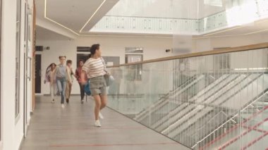 Modern okul koridorunda koşuşturan, günlük giysiler içinde, çok ırklı çocukların yavaşlaması, dersler için acele etmeleri.