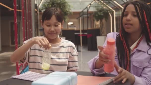 Zwei Unterschiedliche Grundschülerinnen Werfen Der Schulmensa Plastikflaschen Mit Saft Auf — Stockvideo