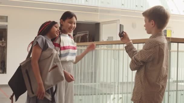 아프리카 미국인 아시아계젠 자매가 카메라를 포즈를 취하는 동급생은 스마트폰을 복도에서 — 비디오