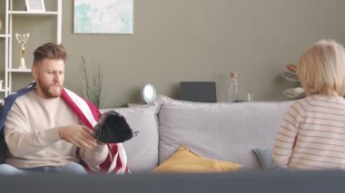 Modern baba ve küçük oğulun TV 'de kanepede oturup birlikte vakit geçirirken beyzbol oynamak için antrenman yapmalarının yavaşlığı.