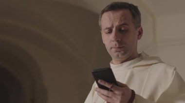 Beyaz cüppeli, kendine güvenen Papa 'nın göğsü ağır ağır kalkıyor. Akıllı telefonunu kullanıyor, gülümsüyor ve ayine gitmeden önce siyah güneş gözlüğü takıyor.