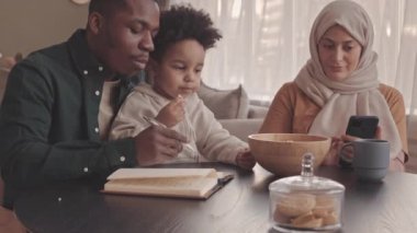 Yeni yürümeye başlayan oğlu ile çağdaş, ırklar arası Müslüman çiftin orta boy bir yavaşlığı aile bütçesini planlamak ve faturaları ve giderleri saymak.