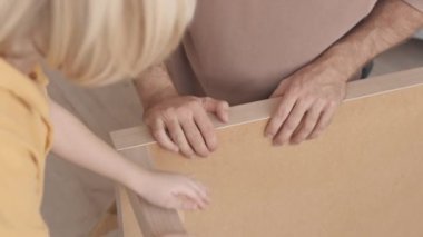 7 yaşındaki Kafkasyalı çocuğun yavaşlığı çekiç kullanırken babama evde DIY ahşap masa kurmasında yardım ediyor.