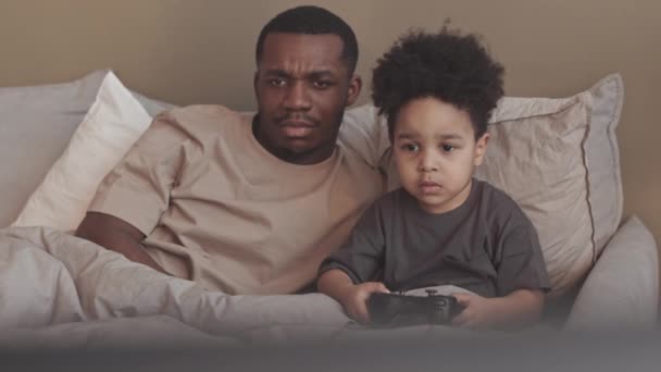 Haftasonu Babasının Yanında Yatağında Kumandayla Video Oyunu Oynayan Afrikalı Küçük — Stok video