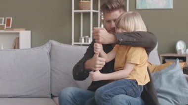 Kafkasyalı bir baba ve küçük oğlu parmaklarıyla kule inşa etmeye çalışırken evde komik oyunlar oynuyorlar.