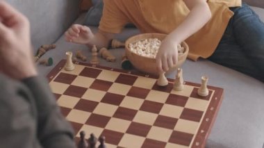 Kafkasyalı baba ve oğlu yavaş yavaş satranç oynuyor ve patlamış mısır yiyor, hafta sonunu evde birlikte geçiriyorlar.