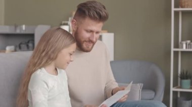 Sekiz yaşındaki güzel kızından el yapımı kartpostal alan sakallı, mutlu, genç, beyaz bir adam. Babalar Günü 'nde babalarını tebrik ediyor.