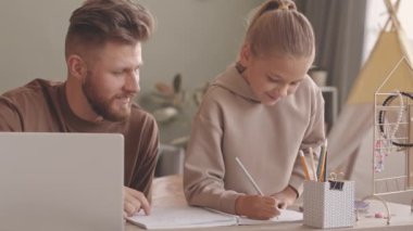 8 yaşında, beyaz, güzel bir kızın ev ödevini yapması ve babasının ona yardım etmesi. Oturma odasında birlikte oturup sohbet etmesi.