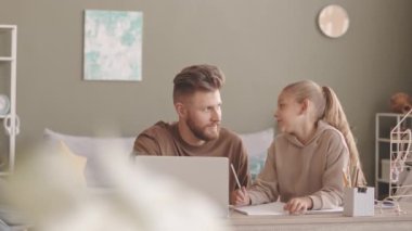 Babanın 8 yaşındaki kızına ev ödevlerinde yardım etmesi, oturma odasındaki laptopun önünde yan yana oturması.