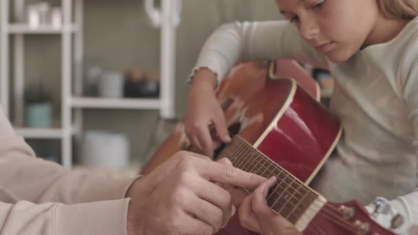 一个聪明的8岁小女孩正在学弹奏吉他 她的父亲在家里帮她练习弦乐 — 图库视频影像