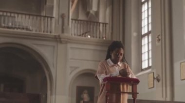 Güzel Katolik kilisesinde elleri bağlı dua eden ve Tanrı 'ya dua eden Afrikalı Amerikalı genç bir kadın yavaşladı.