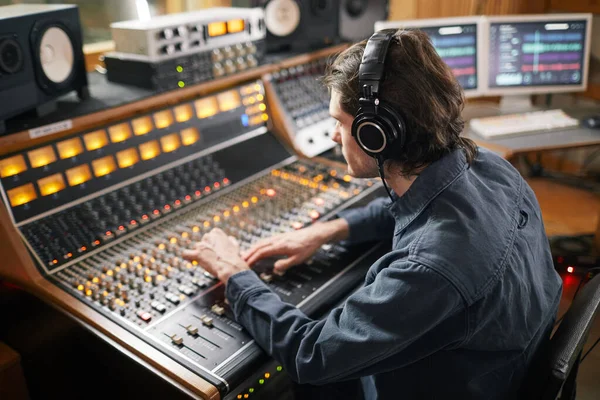 数码音频工作站上戴耳机 操作按钮 切换的年轻人在录音室中的肖像 音乐制作理念 — 图库照片