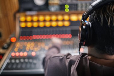 Profesyonel kayıt stüdyosundaki müzik istasyonunda kulaklık takan genç müzisyenlerin arka planı.
