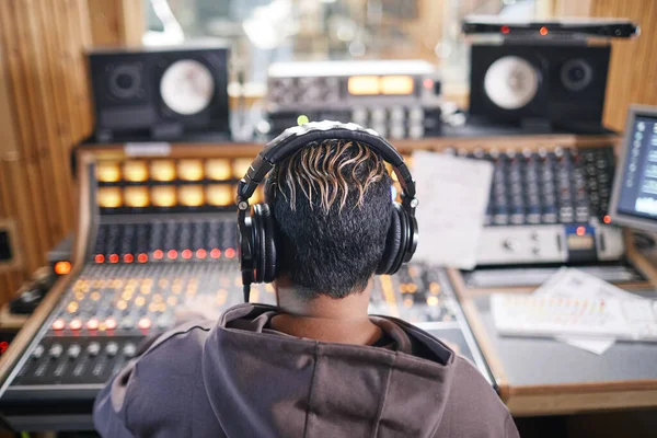 プロのレコーディングスタジオでヘッドフォンを身に着けている匿名の若いミュージシャンでのバックビュー コピースペース — ストック写真