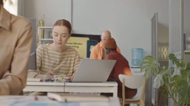 Başarılı dijital pazarlama ajansında çalışan, pazar analizi yapan ve parlak modern ofiste promosyon stratejisi üzerinde çalışan genç profesyonellerden oluşan bir takımın orta yavaşlığı.