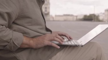 Yazın dışarıda bankta çalışırken dizüstü bilgisayarda yazan tanınmayan işadamı ya da serbest çalışanın orta kesimi