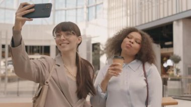 Modern alışveriş merkezinin birinci katında duran akıllı telefondan selfie çeken iki çekici kadının orta boy yavaşlığı.