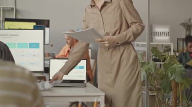 Modern ofisteki işyerlerinde oturmuş şirketin CEO 'sunun hazırladığı yıllık yazılı raporu imzalayan çeşitli pazarlama uzmanlarının yavaşlaması.