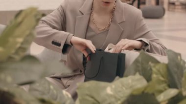 Modern bir mağazadan alışveriş yaptıktan sonra alışveriş poşetlerinin içine bakarken gülümseyen gözlüklü esmer kadın.