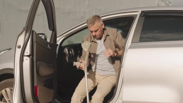 夏の日に車の運転席から出ている間 歩行棒を使用して障害のある成熟した白人男性 — ストック動画