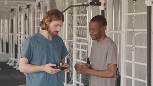 Lentidão Média Fisioterapeuta Caucasiano Com Tablet Paciente Masculino Negro Conversando — Vídeo de Stock