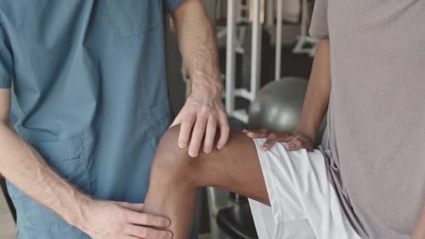 Fizioterapeuta Orvos Felbillenése Kék Köpenyben Fizioterápiás Kezelés Alatt Térdsérüléssel Rendelkező — Stock videók