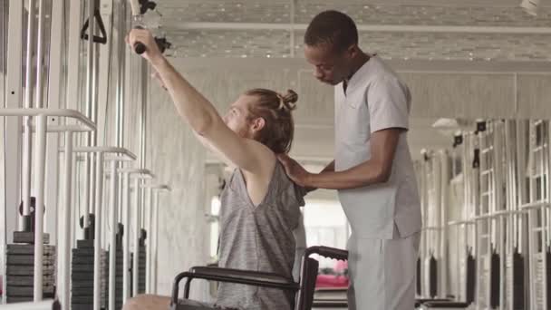 Junger Rollstuhlfahrer Macht Von Seinem Physiotherapeuten Gesteuerte Übungen Einem Hantelgerät — Stockvideo
