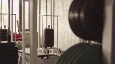 Modern fizyoterapi rehabilitasyon merkezinde spor aletlerine ve ağırlık makinelerine bakan insanlar yok.