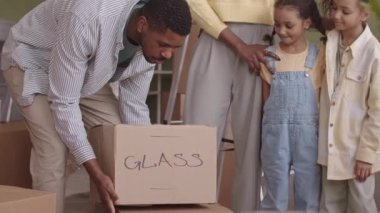 Yeni dairelerinde karton kutuların arasında dikilip etrafa bakınan iki küçük kızı olan modern Afro-Amerikan evli çiftin yavaşlığı.