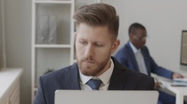 Kafkasyalı erkek tüccar yavaş yavaş akıllı telefondan yatırımcıları ararken ticari platform om laptop üzerinden online borsayı takip ediyor, Afrikalı Amerikalı meslektaşıyla birlikte çalışıyor.