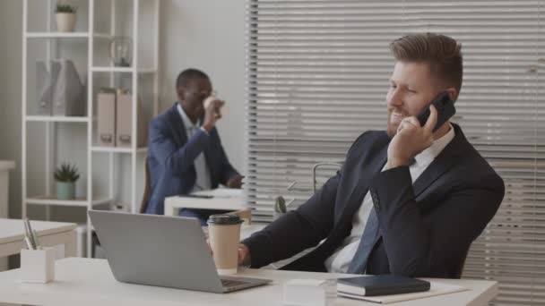 잘생긴 사업가가 스마트폰으로 사무실에 앉아서 아프리카 미국인 동료와 일하고 있습니다 — 비디오