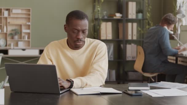 Medium Slowmo Black Man Light Yellow Sweatshirt Sitting Workplace Typing — Stock video