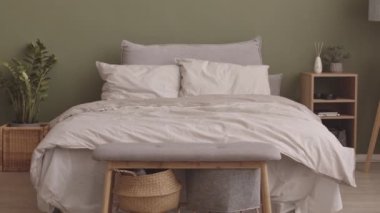 Minimalist eko tarzı yatak odasının içini pastel zeytin yeşili duvarlar, ahşap mobilyalar ve ev bitkileriyle donatan insanlar yok.