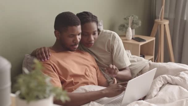 这对年轻貌美的非洲裔美国夫妇躺在床上 用笔记本电脑聊天 — 图库视频影像