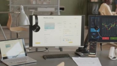 Online borsa ve kripto döviz grafiği olan iki monitör borsa simsarının ofisindeki akıllı telefon ekranında. Arka planda ticaret stratejisini tartışan iki farklı erkek arkadaş